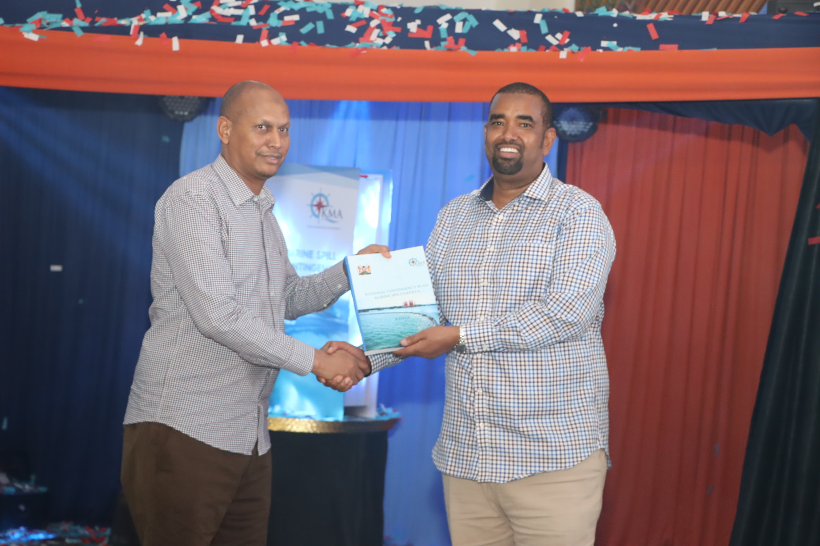 On left, the Principal Secretary State Department for Shipping and Maritime Affairs Aden Millah receiving a copy of the National Marine Spills Response Contingency Plan from the Kenya Maritime Authority Chair Ahmed Kolosh Mohamed.